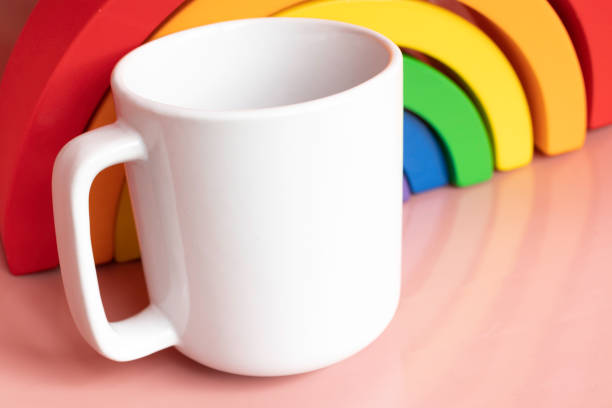 istock Plain blank white 11oz cup in front of a wooden rainbow toy on a pink shiny surface - simple digital mug mock up 1181340477