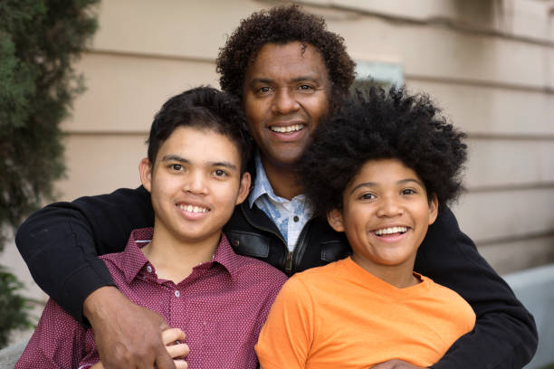 African American father hugging his two sons. Portrait of an African American father hugging his sons. developmental disability diversity stock pictures, royalty-free photos & images