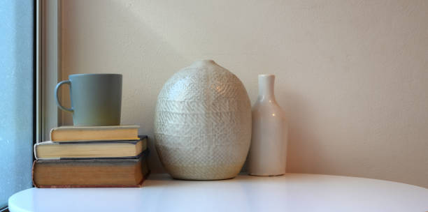 istock Minimal workspace with ceramic vases on white table with books and coffee cup 1181343104