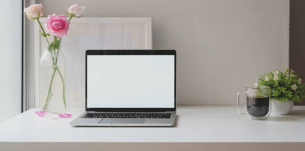 istock Open blank screen laptop computer with mock up frame with roses vase and coffee cup 1181343159