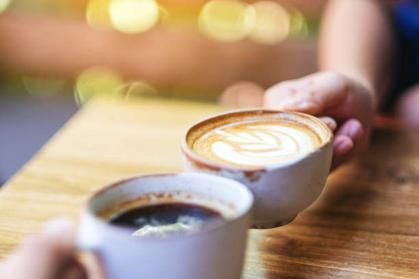 istock two people clinking coffee mugs on wooden table 1181344125