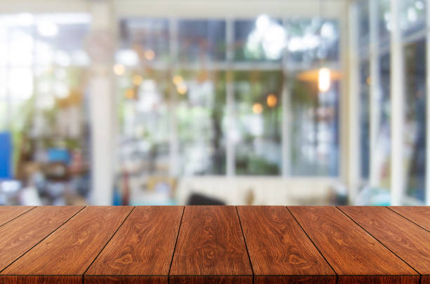 Wood table in blurry background of modern restaurant. Wood table in blurry background of modern restaurant room or coffee shop with empty copy space on the table for product display mockup. Interior restaurant counter design concept. coffee table top stock pictures, royalty-free photos & images