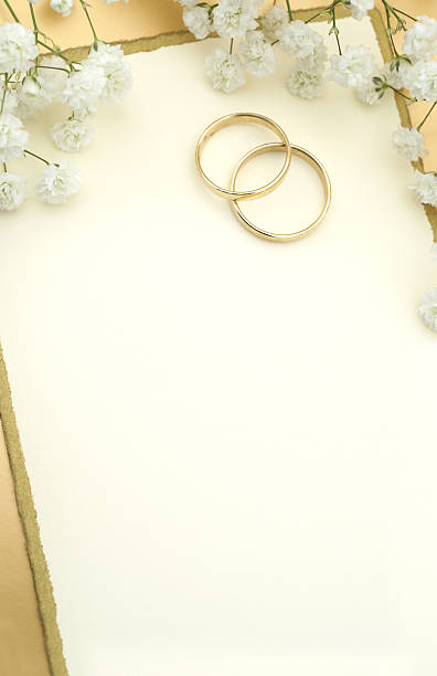 istock Two gold wedding bands under white flowers on white paper 118134763