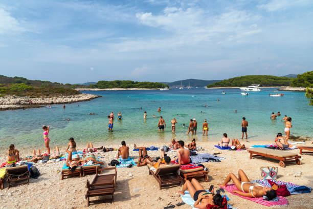 Hvar, Croatia: A popular beach on the island of Hvar in Croatia. Photo taken during a warm summer day and contains people swimming and enjoying the beach.