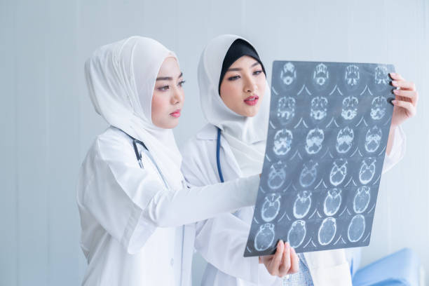 Two woman muslim doctors looking attentively at x-ray of patient and discussing it in hospital stock photo