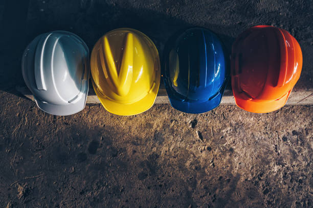 Safety helmet, white, yellow, blue and orange, placed on the cement floor in the construction site. stock photo