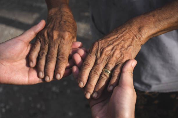 istock Young woman hands holding elderly person's hands. 1181356515