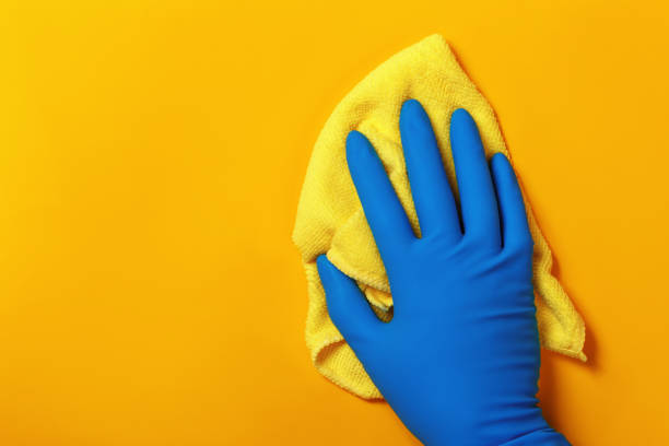 istock A hand in a protective latex glove holds a rag on a yellow colored background 1181359242