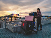 an asian chinese female just arrived at Keflavik Airport waiting outside with beautiful sunset with her luggage