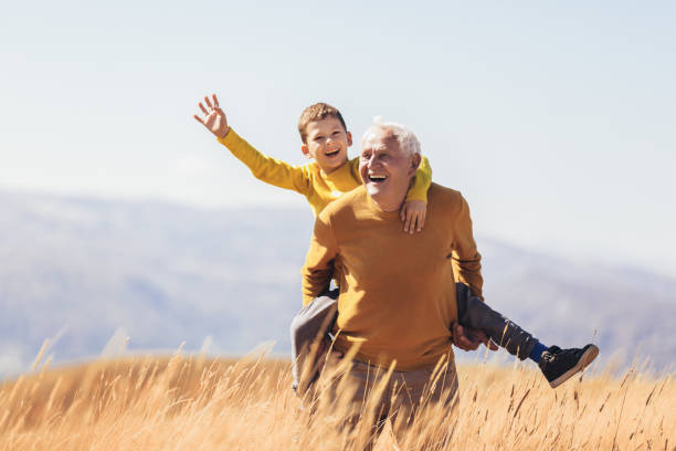 nipote piggyback con suo nonno in autunno. - family happiness outdoors autumn foto e immagini stock