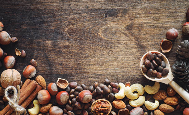 istock Different nuts on a wooden table. Cedar, cashew, hazelnut, walnuts and a spoon on the table. Many nuts are inshell and chistchenyh on a wooden background. 1181368238