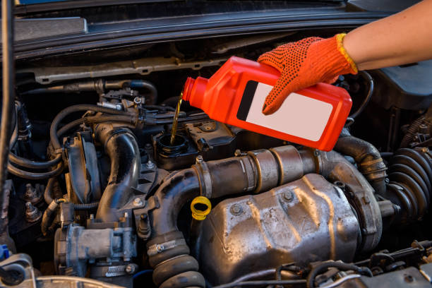 istock Male hands with oil bottle above car engine 1181369667