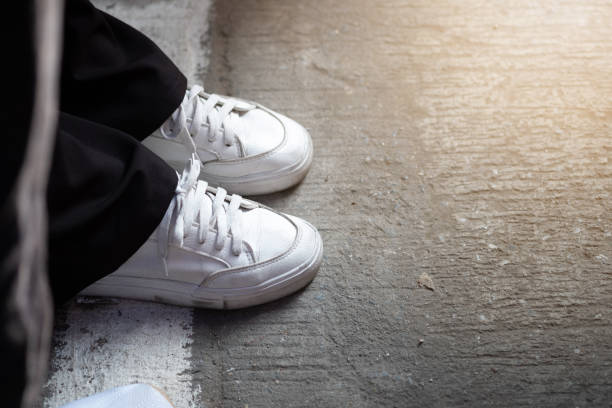 istock White sneakers on asphalt and sunlight in morning time. 1181369785