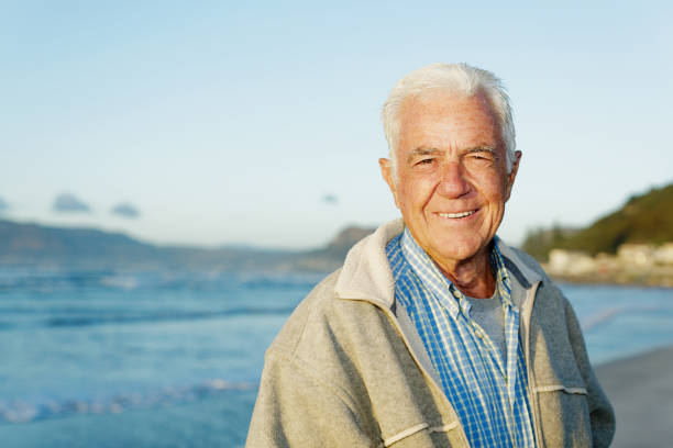 istock Relaxed senior man stands by calm ocean, smiling 1181376321