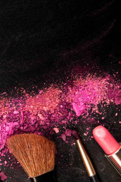 istock Make-up brushes, lipstick, and crushed cosmetics, overhead shot on a black background texture with a copy space, a beauty design template for a makeup banner 1181376614