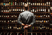 Bartender at wine cellar full of bottles with exquisite drinks