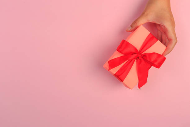 istock gift in female hands on a colored background top view. 1181377524