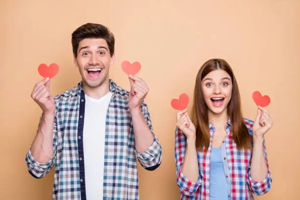 Photo of casual cheerful red redhair stylish cute charming beautiful couple, rejoicing about having received new small red post cards isolated over beige color pastel background