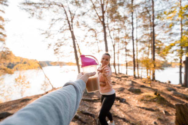 Woman drinking a protein shake after outdoor workout