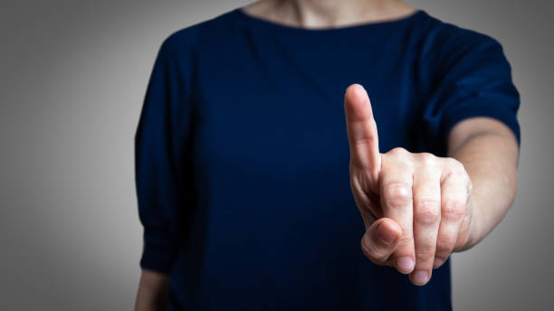 Woman with pointing to something or touching a touch screen Woman with pointing to something or touching a touch screen on gray background clicking screen stock pictures, royalty-free photos & images