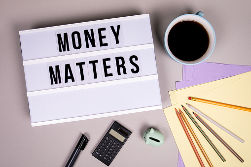 Money Matters. Finances, revenue, economy and profit concept. White lightbox on a gray office desk