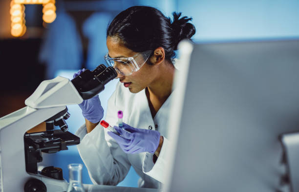 young scientist looking through a microscope - science women female laboratory imagens e fotografias de stock