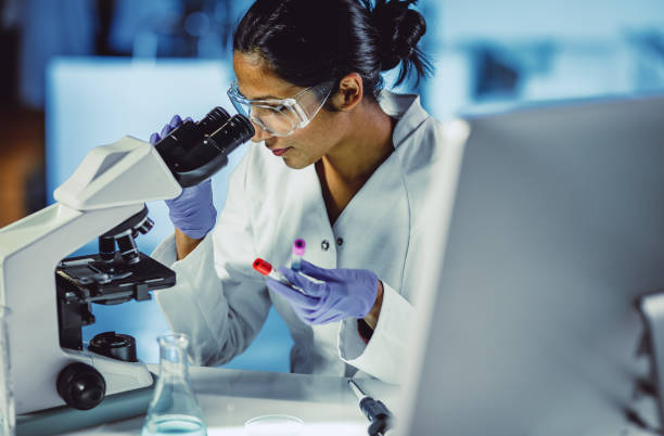 young scientist looking through a microscope - hematology imagens e fotografias de stock