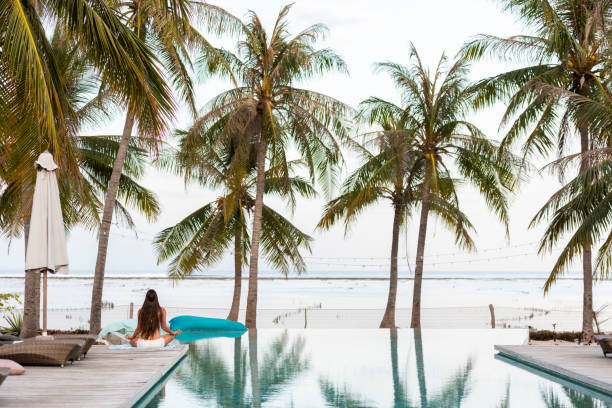 istock Woman meditates on deck by infinity pool 1181392491