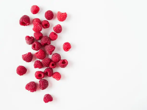 Heap of fresh ripe red raspberries on white background. Raspberry with copy space for text or design. Top view or flat lay.