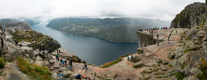 Pulpit rock - Preikestolen - Norway. Walking routes, exploration and activities of tourists, mountaineers and travelers. Tourist attraction. Crowds of tourist go on a hike to reach the rock.