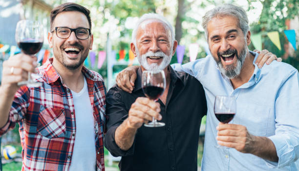Cheers! Happy three men drinking red wine outdoor on garden party father son grandfather fathers day stock pictures, royalty-free photos & images