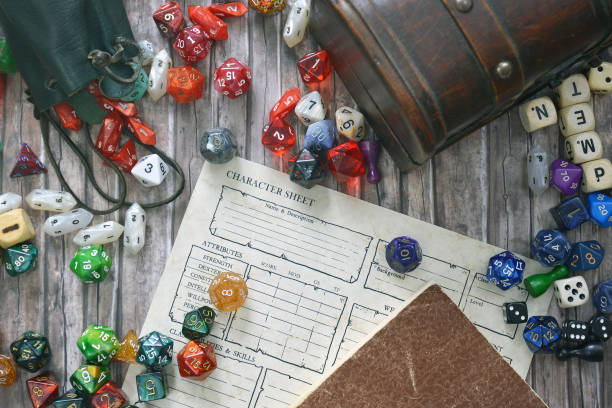 Tabletop roleplaying flat lay with colorful RPG and game dices,  character sheet, rule book and treasure chest on wooden desk RPG flat lay dice photos stock pictures, royalty-free photos & images