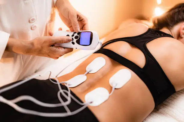 Lower Back Physical Therapy with TENS Electrode Pads, Transcutaneous Electrical Nerve Stimulation. Electrodes onto Patient's Lower Back