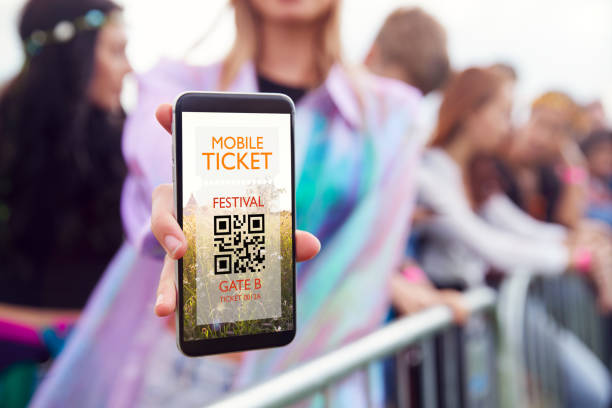 Close Up Of Woman Holding Mobile Phone Screen To Camera As She Arrives At Entrance To Music Festival Close Up Of Woman Holding Mobile Phone Screen To Camera As She Arrives At Entrance To Music Festival ticket photos stock pictures, royalty-free photos & images