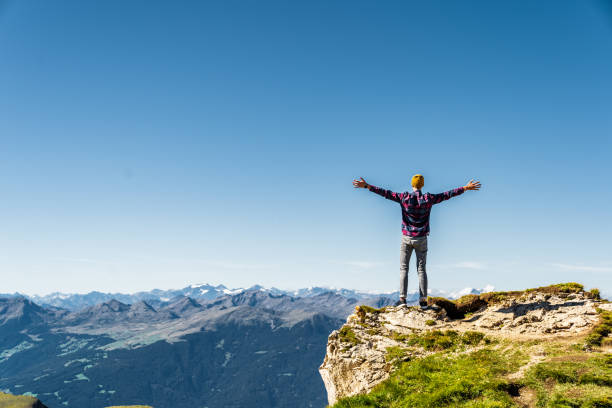 mann, der mit erhobenen händen am rand des felsens steht. italienische alpen in der nähe der ceceda. - european alps mountain mountain peak rock stock-fotos und bilder