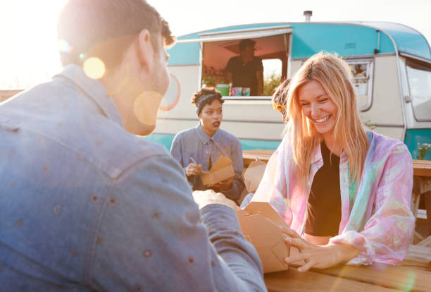 Group Of Friends Eating Takeaway Food From Truck At  Outdoor Music Festival Group Of Friends Eating Takeaway Food From Truck At  Outdoor Music Festival food festival stock pictures, royalty-free photos & images