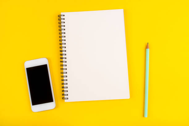 istock Empty notebook, pencil and phone on yellow background, top view. 1181405447