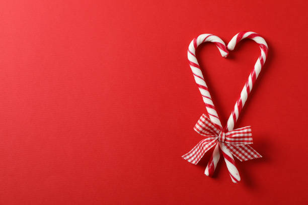 istock Sweet candy canes with bow on red background, space for text 1181407262