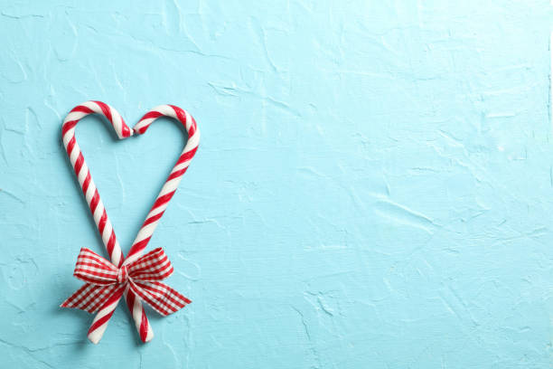 istock Sweet candy canes with bows on blue background, space for text 1181407330