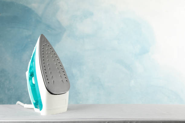 istock Iron on ironing board against blue background, space for text 1181408600