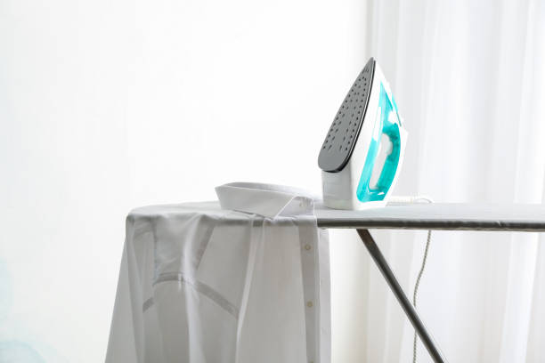 istock Iron and shirt on ironing board, space for text 1181408641