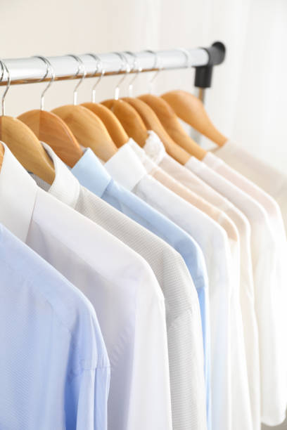istock Hangers with shirts against light background, close up 1181409366