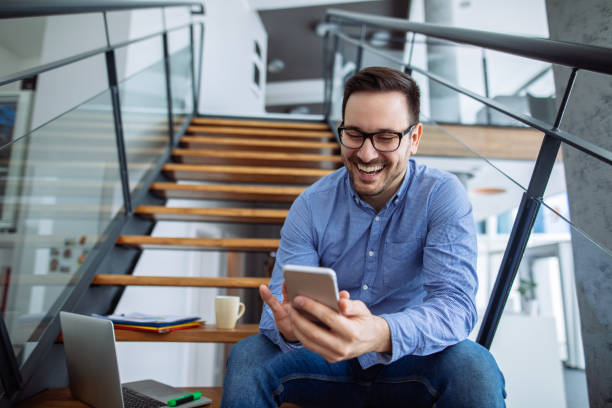 istock Businessman sitting on the stairs and text messaging 1181409396