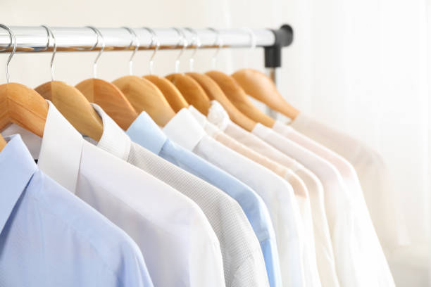 istock Hangers with shirts against light background, close up 1181409441
