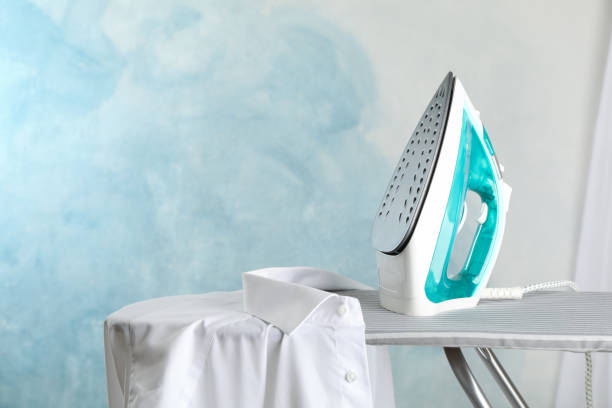 istock Iron and shirt on ironing board, space for text 1181409465