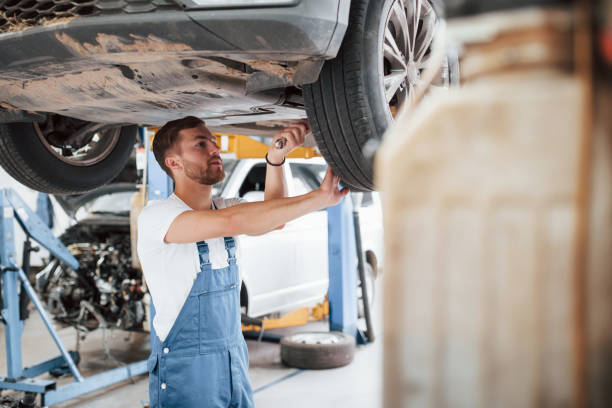 istock Using a wrench. Employee in the blue colored uniform works in the automobile salon 1181409882