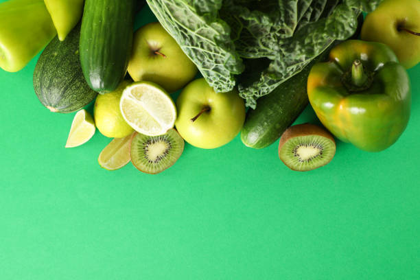 Vegetables and fruits on green background, copy space