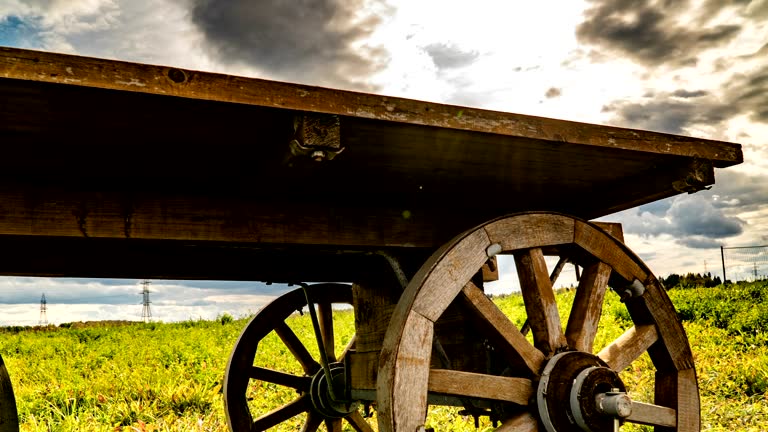 Antique wooden cart standing alone in a field, beautiful autumn landscape, hyperlapse, time lapse, heavy autumn sky