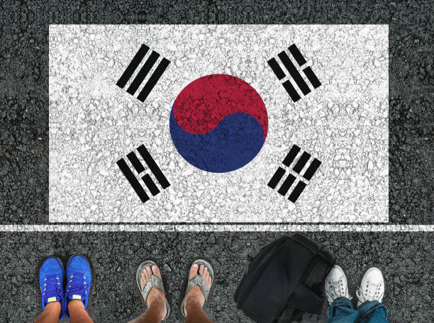people legs are standing on asphalt road next to flag of South Korea and border