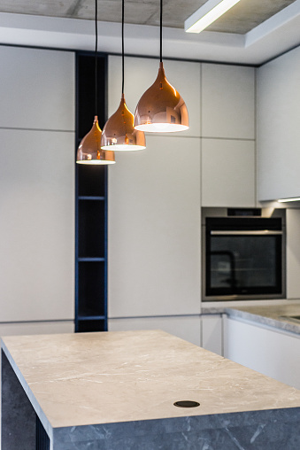 Modern kitchen, grey facade, three lamps over kitchen island.